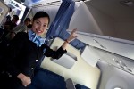 ANA flight attendant demonstrates the new overhead baggage compartment.