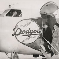 Bump Holman stands in front of the DC-3 with Lee Pike, his first flight instructor and first co-pilot with the Dodgers in 1954. Holman got his commercial pilot’s license at the age of 18. Photo by Barney Stein 	     	The Brooklyn Dodgers Convair 440 Metropolitan twin-engine plane was purchased on January 4, 1957. The Dodgers took delivery of the plane in mid-March. At the time of purchase, Dodger President Walter O’Malley announced to Associated Press, “This is the first time a major league club has bought an airplane.” 	     	Dodger President Walter O’Malley and Dodger Director Bud Holman are on the steps of the 44-seat Dodger Convair 440 Metropolitan twin-engine plane. Holman’s son Bump is visible in the cockpit window. O’Malley added to the order of Eastern Air Lines to purchase the plane directly through the Convair factory, with the assistance of his friend Capt. Eddie Rickenbacker, President of Eastern. Bud Holman served as a Director of the Dodgers and was Eastern’s representative at the Vero Beach Airport. 	     	The Dodgers became the first major league baseball team to own their own airplane, as they purchased a Convair 440 Metropolitan twin-engine. From left to right, Capt. Eddie Rickenbacker, President of Eastern Air Lines, Dodger Director Bud Holman, Dodger President Walter O’Malley and Dodger Director James Mulvey show a model of the Convair 440. The Dodgers made the purchase of the airplane on January 4, 1957, piggybacking on Rickenbacker’s order of airplanes for Eastern.