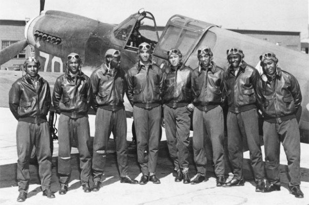Eight Tuskegee Airmen pose in front of a P-40, circa May 1942 to Aug 1943.