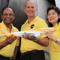 Scoot executives pose with a model Boeing 777 with a full-size version in the background. (Photo by Scoot)