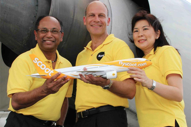Scoot executives pose with a model Boeing 777 with a full-size version in the background. (Photo by Scoot)