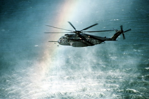 A rainbow is formed in the mist rising from the ocean as a Helicopter Mine Countermeasures Squadron 15 (HM-15) MH-53E Sea Dragon helicopter conducts mine countermeasures operations near Naval Air Station, Alameda, Calif. (Photo by John Gaffney/US Navy)
