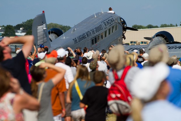 The crowd looks to the sky in unison at the F18 above them while the JU-52 rests.