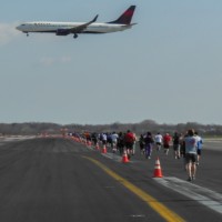 A Delta Boeing 737 on short final for runway 31R as JFK Runway Run participants run down runway 4R.