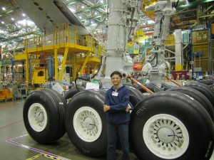 Aditya stands with the landing gear for a 747-8 during a VIP factory tour.