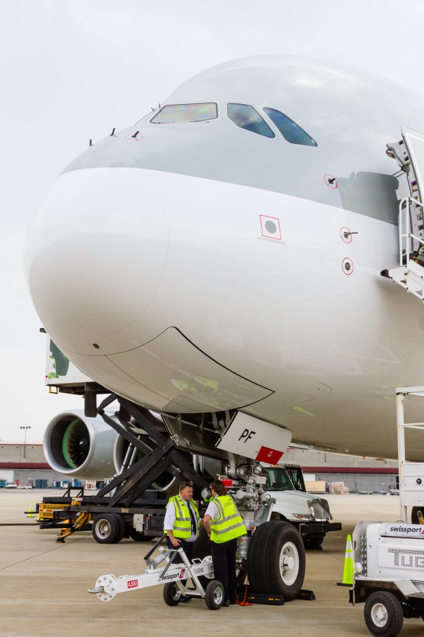 Personnel stand under the nose of the superjumbo while the aircraft is serviced. 