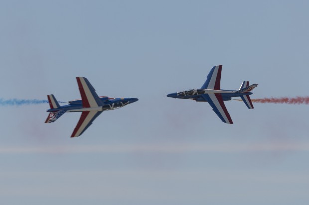 The two Patrouille de France solos cross while rolling at show center.