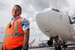 Ramp duty manager Albert Cordeschi (“Ramp Ringleader”) poses on the runway underneath an airplane. (Photo by Travel Channel)