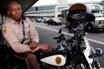 Miami-Dade County motorcycle officer Stretch Rutledge (“MIA’s Gentle Giant”) poses on his motorcycle by the departures drop-off at MIA. (Photo by Travel Channel)