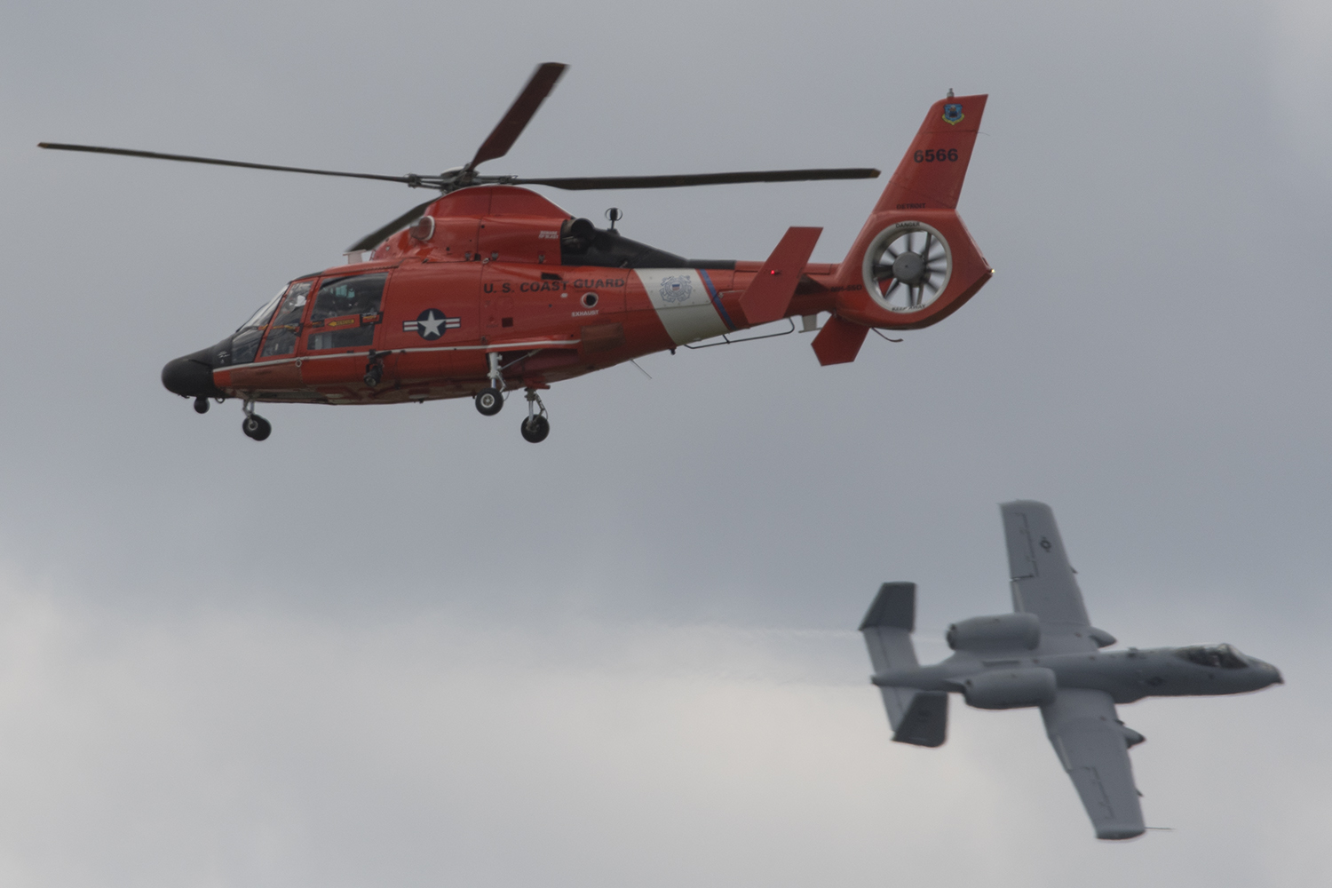 A USCG Air Station Detroit MH-65D approaching a “downed aviator” as an A-10 flies top cover.