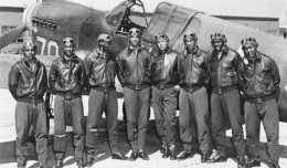 Eight Tuskegee Airmen pose in front of a P-40, circa May 1942 to Aug 1943.