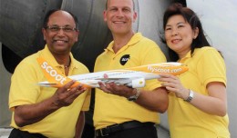 Scoot executives pose with a model Boeing 777 with a full-size version in the background. (Photo by Scoot)