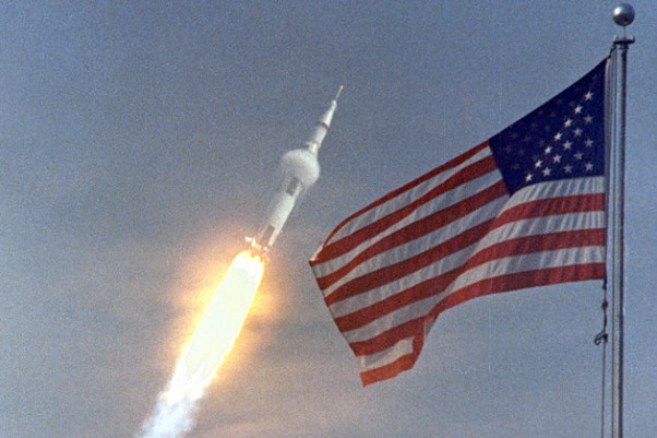 Apollo 11 flies towards earth orbit with the American flag in the foreground. (Photo by NASA)