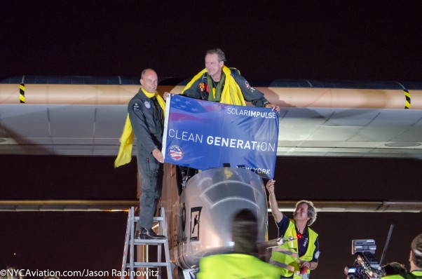 The Solar Impulse crew holds up a banner after completing their cross crountry journey